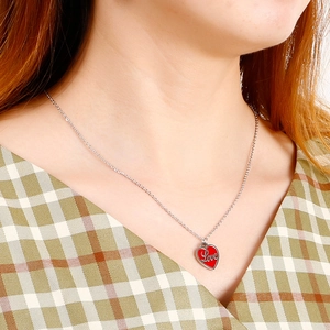 Gros plan d'un collier en acier argenté avec pendentif cœur rouge et gravure Love élégante