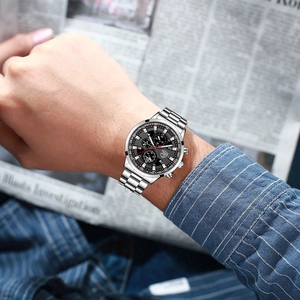 Close-up of a silver stainless steel watch with a black dial worn on a male wrist