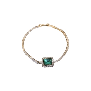 Elegant gold bracelet with square emerald green zircon and diamond halo on white background