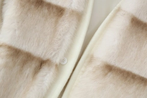 Detailed close-up of faux fur collar and round button on a striped beige wool coat