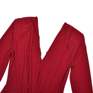 Détail macro de la robe rouge pailletée avec décolleté en V et plis aux épaules