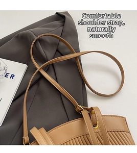 Detail view of khaki shoulder bag with vertical pleated texture and golden metal hardware