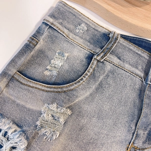 Dettaglio ravvicinato di pantaloncini in denim azzurro con bordi sfilacciati e trama usurata