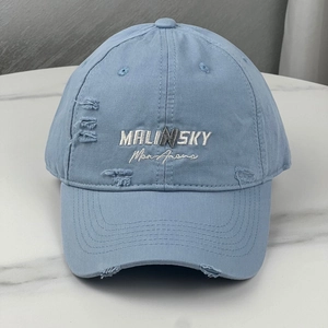 Close-up of Malinsky embroidery and distressed fabric details on light blue baseball cap