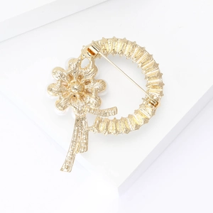 Macro detail of gold flower brooch back showing safety pin clasp and pearl setting