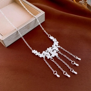 Detail of silver floral necklace featuring hollow petal links and elegant tassel fringes