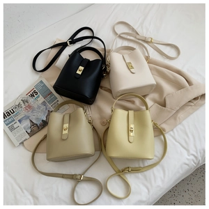 Detail view of stylish bucket bags in black, white, beige, and yellow with metal hardware