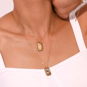 Detail of layered gold necklaces with Sun and Temperance tarot card pendants on a model
