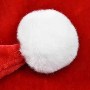 Macro detail of a soft white plush pom-pom and vibrant red velvet texture on a Christmas hat
