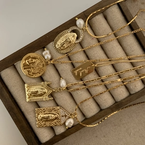 Detailed shot of vintage gold Virgin Mary pendant necklaces with pearls and coin charms