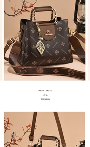 Detail of a textured dark coffee leather bag with floral print and golden leaf pendant