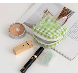Detail of green and white plaid quilted cosmetic bag with cosmetics on a magazine