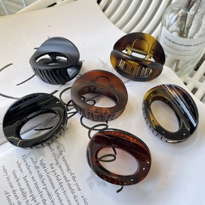 Detailed arrangement of diverse oval hair claws in matte black and tortoiseshell finishes