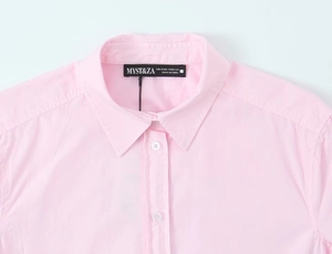 Detailed close-up of the collar and neckline label on this light pink poplin shirt