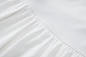 Macro shot showing detail of white pleated fabric texture and craftsmanship on summer dress
