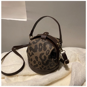 Detail of leopard print bucket bag with brown leather trim and gold metal hardware