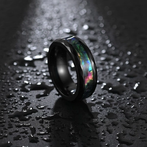 Macro shot of black faceted titanium ring with iridescent abalone shell inlay and water drops