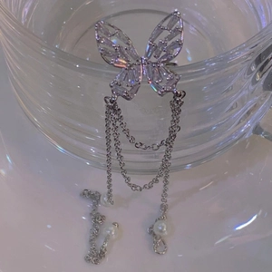 Vue détaillée d'un ear cuff papillon argenté avec zircon et glands de perles