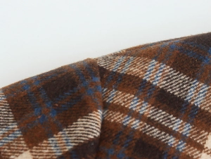Macro shot showing the detailed brown and blue plaid wool texture of the coat fabric