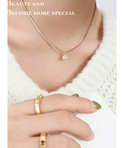Close-up of gold-plated necklace with sparkling zircon pendant on model
