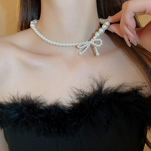 Close-up of elegant pearl bow necklace showing cream white beads on a woman's collarbone
