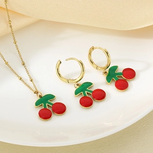Gros plan sur l'ensemble de bijoux cerise avec pendentifs en émail rouge sur assiette