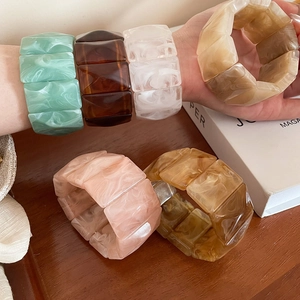 Close-up of geometric acrylic bangle with colorful marble and amber resin textures