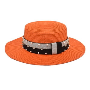 Detailed close-up of an orange straw boater hat featuring pearl and rhinestone accents