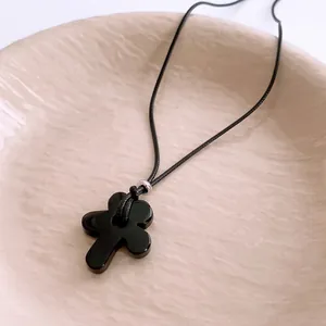 Vintage wax rope necklace with black floral tiger eye pendant on a ceramic tray
