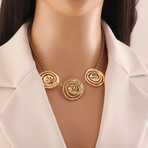Detail shot of a golden necklace with three rose pendants worn with a beige blazer