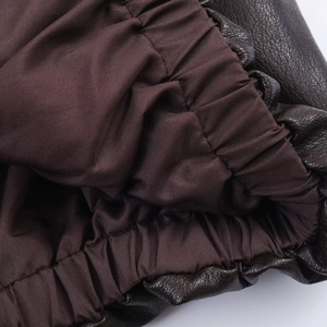 Detailed close-up of dark brown faux leather jacket with elastic hem and polyester lining