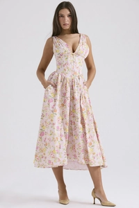 Detail shot of a V-neck summer floral dress with functional side pockets on pink fabric