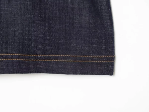 Detailed view of dark blue denim hem with orange double stitching on casual mini dress
