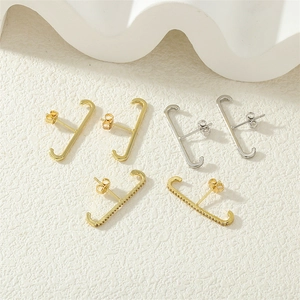 Detailed view of gold and silver J-shaped earrings with micro-inlaid cubic zirconia