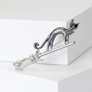 Detailed close-up of flying broom cat brooch with sparkling rhinestone accents