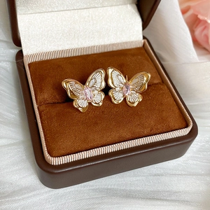 Detail of golden butterfly earring with pink gemstone in premium jewelry gift box