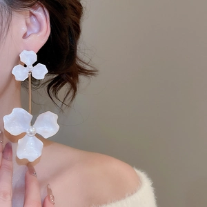 Detail of elegant white double flower drop earrings with pearls on a model