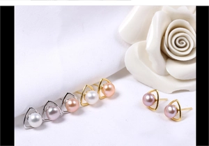 Macro detail of triangle silver earrings with natural freshwater pearls on white fabric