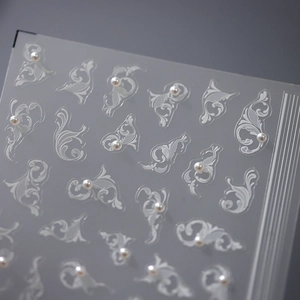 5D stereoscopic white filigree nail stickers with faux pearls on soft blue background