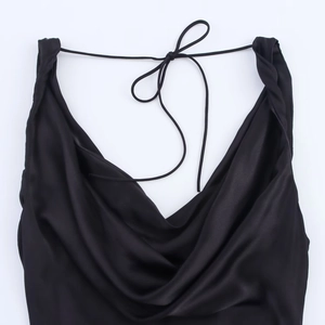 Detail of black satin dress showing elegant cowl neckline and slim tie-up straps