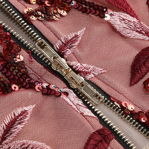 Detail of red sequins, leaf-shaped embroidery and gold zipper on elegant dress