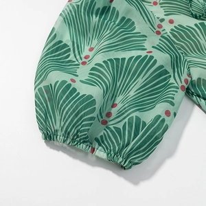 Detail of chiffon dress elastic cuff with green ginkgo leaf print and red dots
