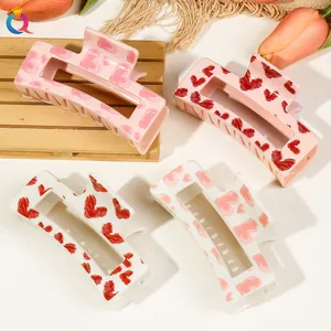 Detail of rectangular hair claws with red and pink heart patterns on wooden tray