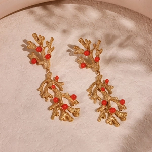 Irregular 18k gold plated coral branch earrings with red beads on a stone surface