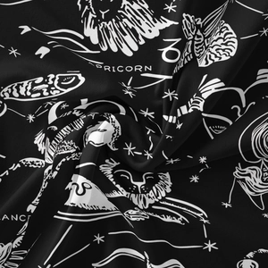 Close-up of black bohemian tapestry fabric with white Capricorn zodiac star signs