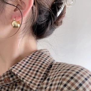Close-up of minimalist gold semi-spherical stud earring worn by a model