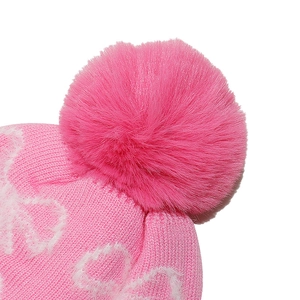 Detail of soft pink faux fur pompom and delicate knit texture on children winter hat