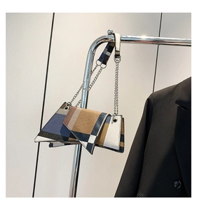 Detail view of contrast plaid crossbody bag with silver chain and wide fabric strap