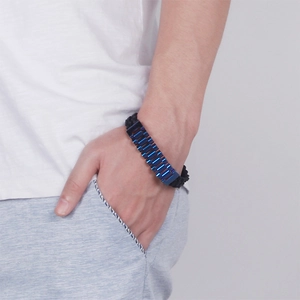 Close-up of men's blue titanium steel chain and black braided rope bracelet on wrist