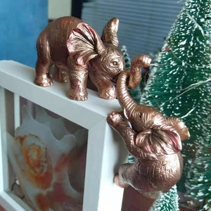 Detailed view of bronze resin elephant figurines climbing on a white frame